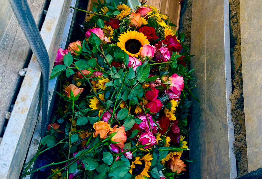 Blumenschmuck auf einem Holzsarg im Grab
