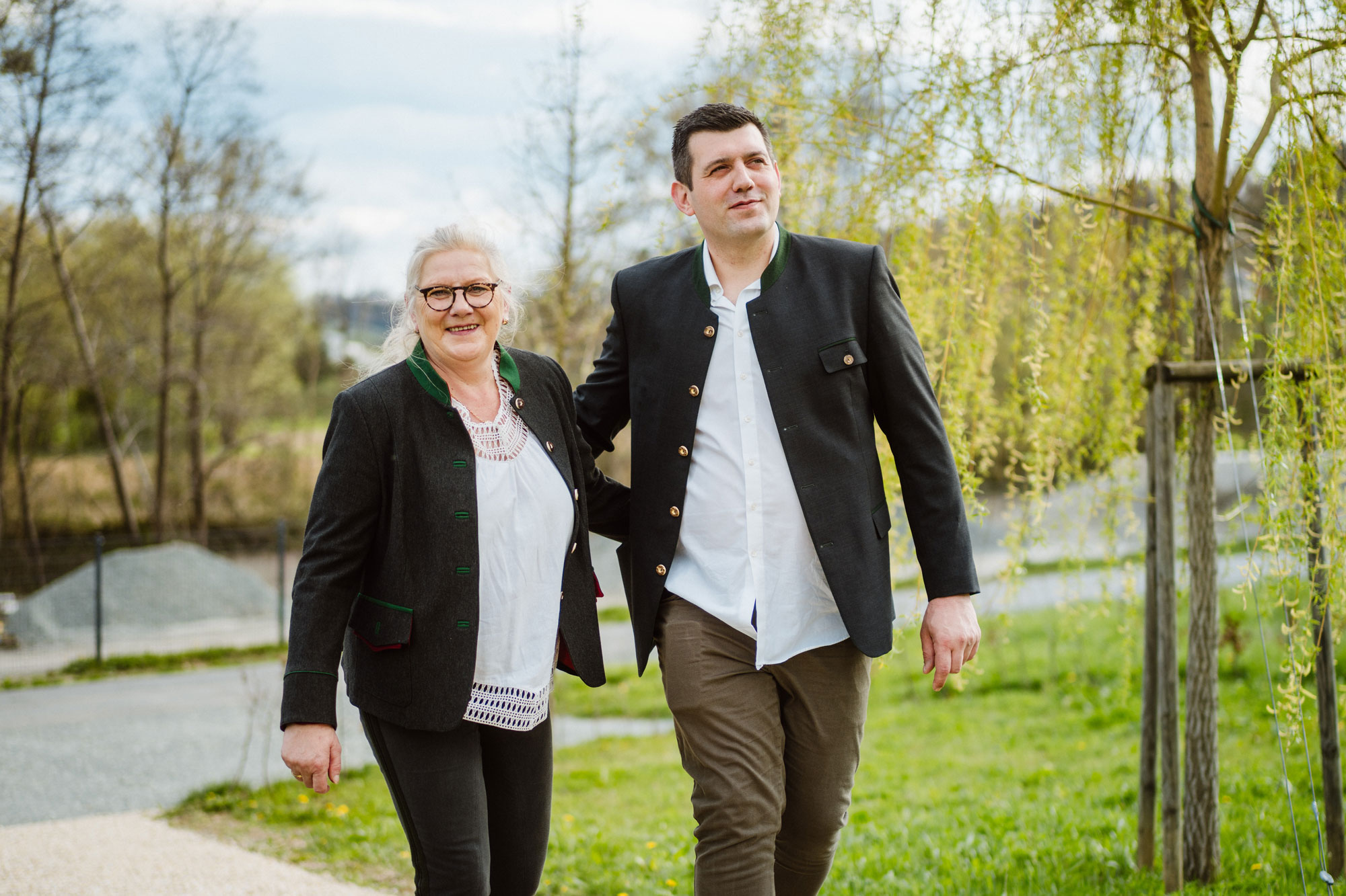 Monika und Philipp Michael Neubauer Arm in Arm in grüner Natur gehen den Weg entlang